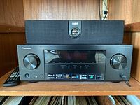Pioneer VSX-524 AV receiver with RCA RT2250 speaker on top and the remote control beside the receiver.