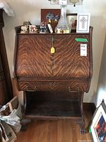 Front view of the oak secretary desk showing the closed drop-front and carved claw feet.