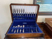 Open wooden flatware box showing velvet-lined interior with flatware