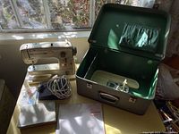 Machine, open case, manual, foot pedal and cord on tabletop