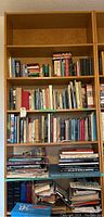 Front view showing 6 shelves filled with books and some clutter at the bottom for size reference.