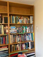 Front view of the full 6-tier wood bookcase filled with some books and binders (contents not included in sale).