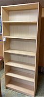 Front view of the full bookshelf, showing six shelves, five adjustable, light wood finish.