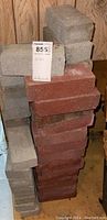Stack of gray concrete bricks and red clay bricks with MaxSold lot tag in photo.