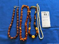 Four gemstone bead necklaces laid out showing variety in bead color, shapes, and clasps, including a note card describing the lot contents and measurements.