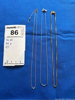 Overview of three chain necklaces laid out on blue background