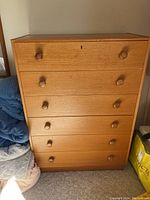 Front view of the mid-century modern wooden 6-drawer dresser with round wooden knobs showing scratches and scuffs.