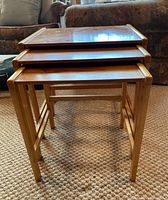 Front view of the three stacking tables nested together, showing size progression and teak wood finish