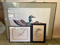 Overall photo of three framed Native American art lithographs including one large bird print and two smaller framed prints