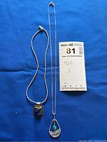 Two necklaces placed on blue background with a label showing '925' and number 2, indicating sterling silver content and quantity.