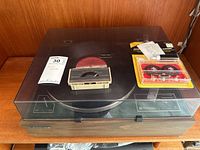 Overview of Toshiba turntable with closed dust cover, accompanying accessories placed on top of dust cover.