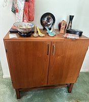 Front view of the vintage wood record cabinet revealing two doors with metal handles and medium brown wood finish.