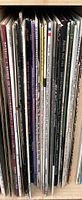 Photo showing spines of various vinyl records including titles: Barber of Seville, Mozart concertos, and others in the rack.