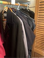View of six women's coats on hangers showing different styles and colors