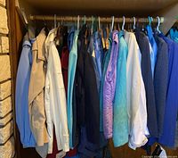 Photo of women's jackets hanging on hangers in a closet showing various colors and styles including blue, beige, white, and purple.