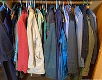View of women's jackets in multiple colors hanging on rod, including coral pink, cream, blue, and green jackets.