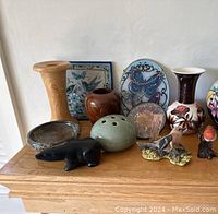 Various signed pottery vases, Mexican pottery dish, suncatchers, animal and bird figurines arranged on a wooden surface