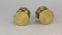 Front view of a pair of octagonal gold cufflinks with etched Art Deco design and border detail.