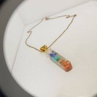 Top view image of multi stone pendant necklace with gold-tone chain on white background.