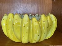 Side view of the Fitz & Floyd yellow banana bowl showing detailed ceramic bananas and scalloped inner edge.