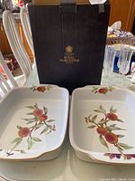 Two Royal Worcester Evesham baking dishes with fruit patterns in front of Royal Worcester branded box.