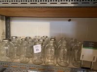 Shelf with multiple clear glass canning jars with metal lids, arranged in rows