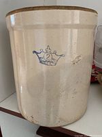 Side view of the vintage stoneware crock showing crown emblem with number 2 and some surface chips.