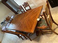 Overview of rectangular extendable table and six matching chairs on tile floor