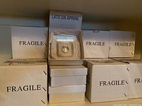Boxes labeled 'Fragile' containing individually boxed glass plates with tissue paper inside.