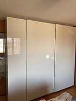 Exterior view of three-module PAX wardrobe with high gloss white doors.