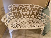 Front view of white iron loveseat bench against wall
