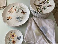 Top view showing two styles of Lenox plates stacked separately and two embroidered cloth napkins folded beside