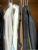 Photo showing five men's jackets hanging on hangers, various colors including black, white, gray, and brown.