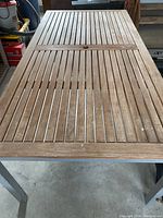 Top view showing the wooden slatted patio table surface with a weathered look and central hole for umbrella.