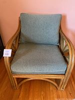 Front view of rattan armchair with blue-green cushions.