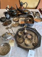 Overview of all items laid out on table including tea set, trays, spoons, bud vase, boxes