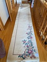 Full view of the hallway runner rug laid out on hardwood floor, showing entire length and floral design on cream background.