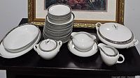 Full display of the fine china dinnerware set arranged with plates stacked and serving pieces placed around.