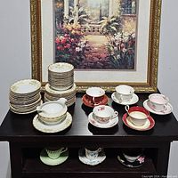 Two sets of china teasets displayed with cups, saucers, small plates, creamer, and sugar bowl.