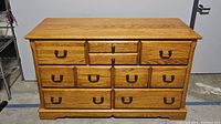 Front view of oak dresser with seven drawers and metal handles, showing overall condition and style