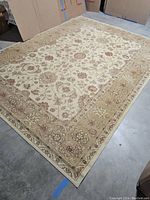Full view of the beige floral area rug showing overall pattern and size in the room.