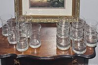 Top-down view of 16 clear glass tumblers grouped by size on wooden table
