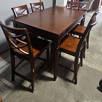 Seven piece dining set with table and six chairs shown from an angle highlighting chair design and table top.