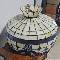 Side close-up showing the top petal-shaped glass pieces and band of dark blue squares around the pendant.