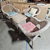 Three light beige woven wicker armchairs and one matching square wicker table arranged together, showing the set and cushions.