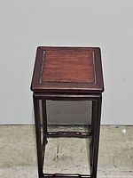 Front view of the small wooden plant stand showing square top and slender legs with cross braces
