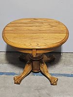 Front view of the wooden round pedestal side table on claw foot legs, showing the top and base.