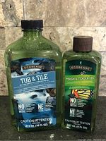 Two sealed bottles of Melaleuca EcoSense cleaners, Tub & Tile and Tough & Tender, on tile background.