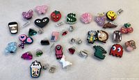 Lot of 36 assorted new shoe charms shown spread out on white surface