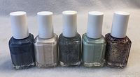 Five bottles of new Essie nail polish in different colors lined up side by side on a white background